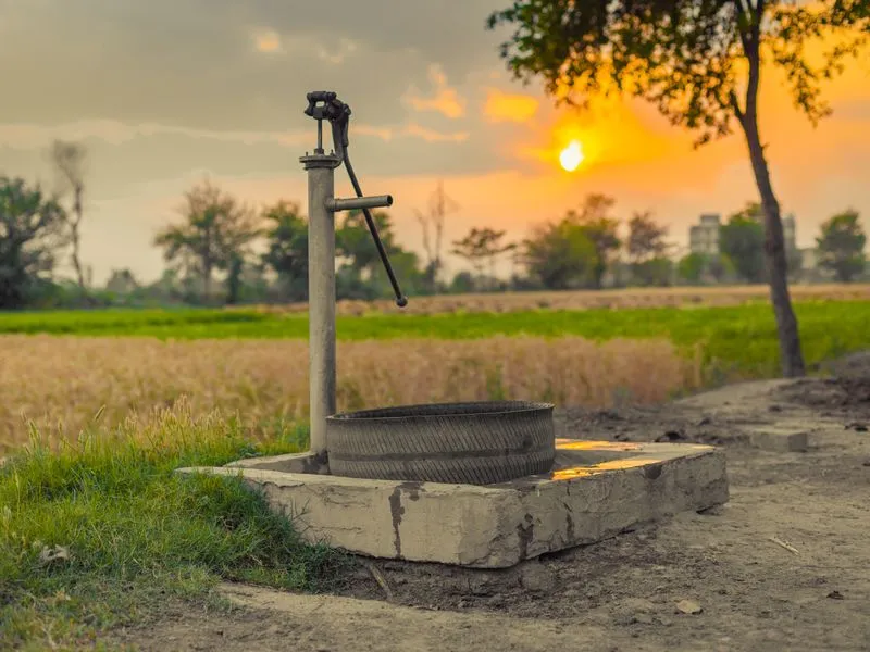 Hand pump in a field at sunset